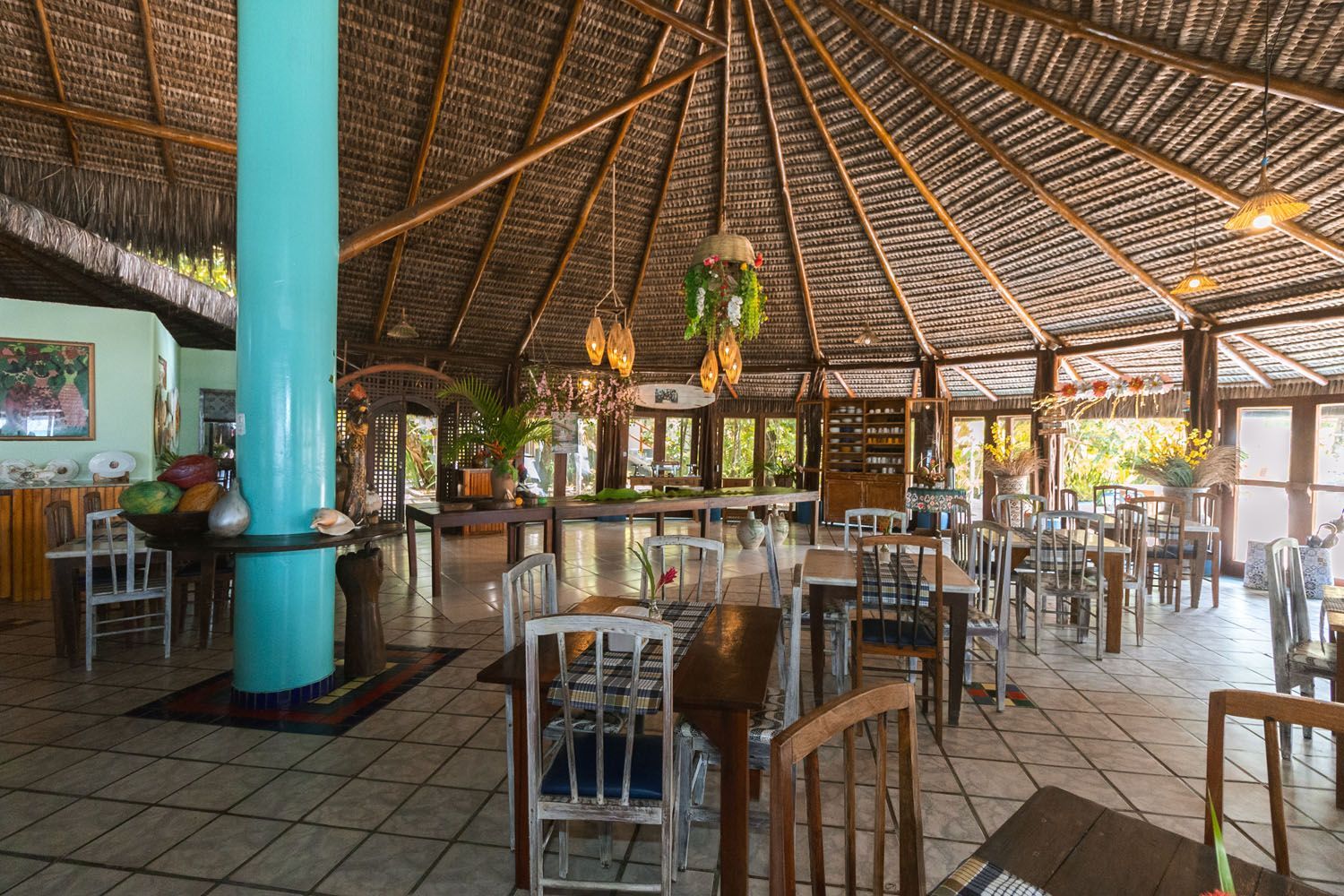 Um restaurante com mesas e cadeiras e um telhado de palha.