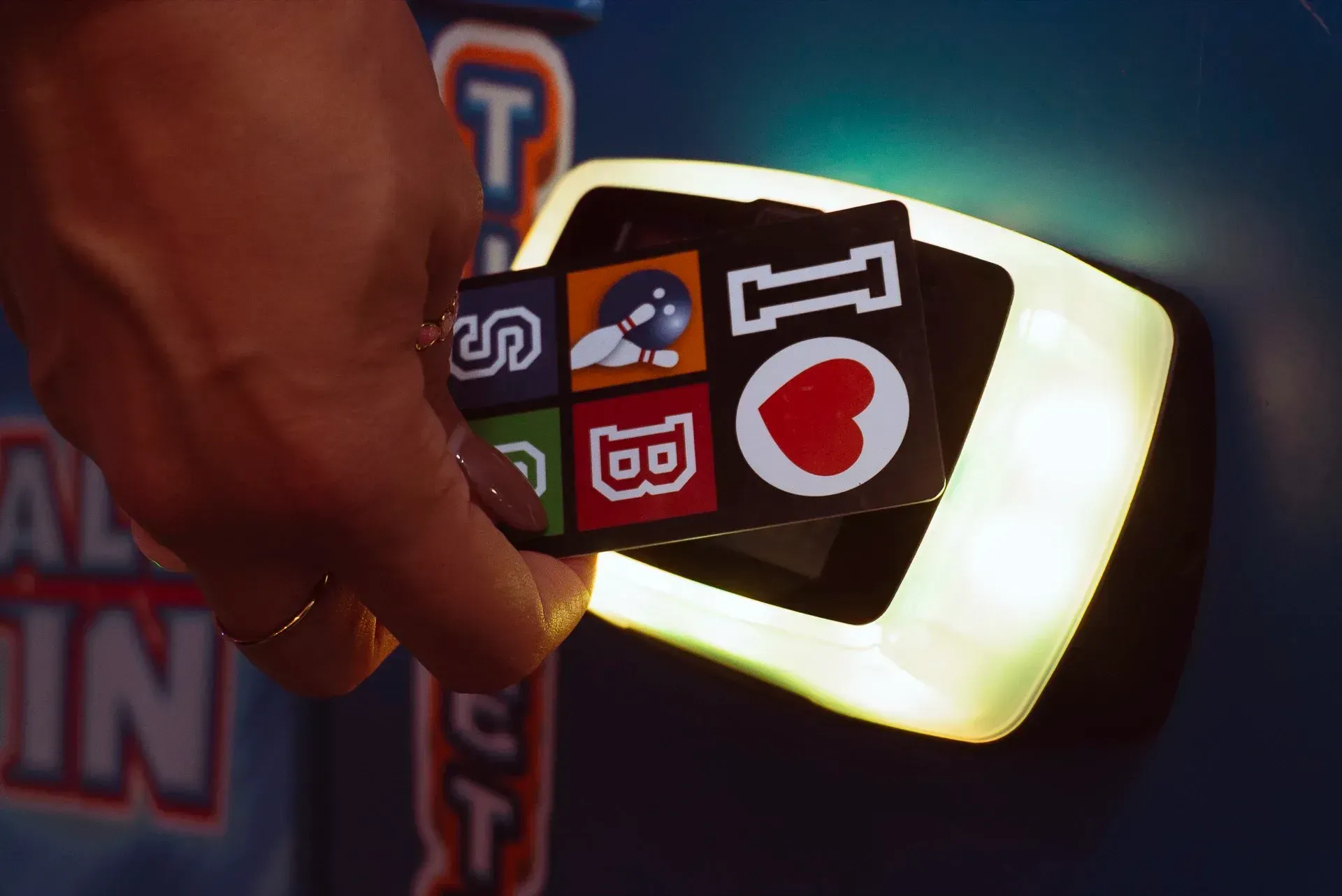 Una persona inserisce una scheda di gioco con icone colorate in un lettore luminoso di una console per videogiochi.