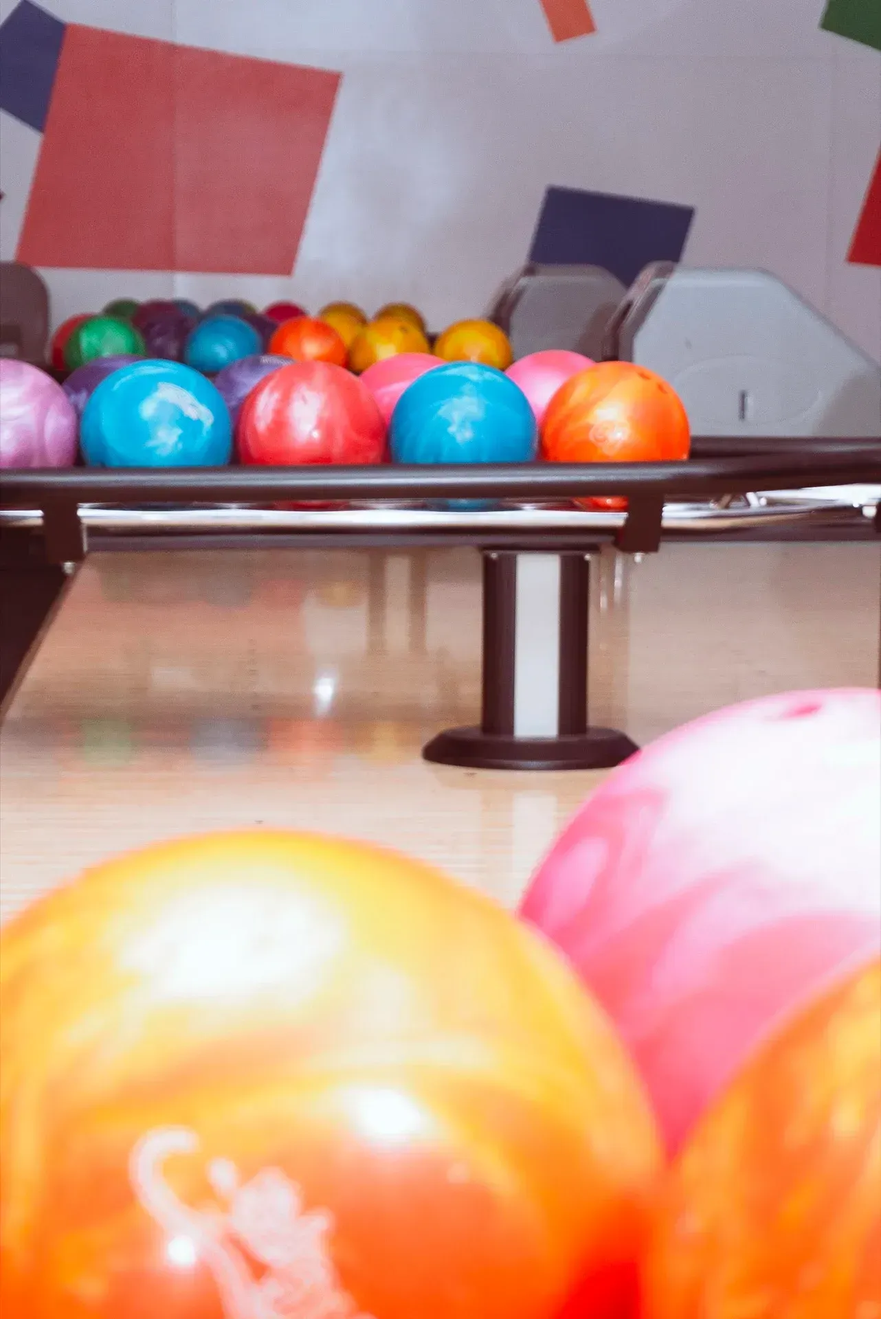 Palle da bowling su un supporto, alcune in primo piano, con un sistema di ritorno automatico delle palle sullo sfondo.