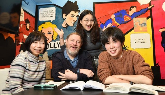 一群の人々がノートパソコンを持ってテーブルに座っています。