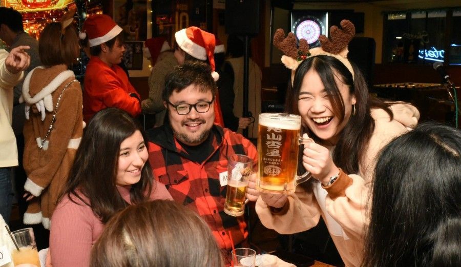 A group of people are sitting at a table holding glasses of beer.