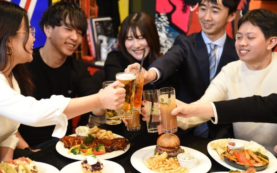 A group of people are sitting at a table with plates of food and drinks.