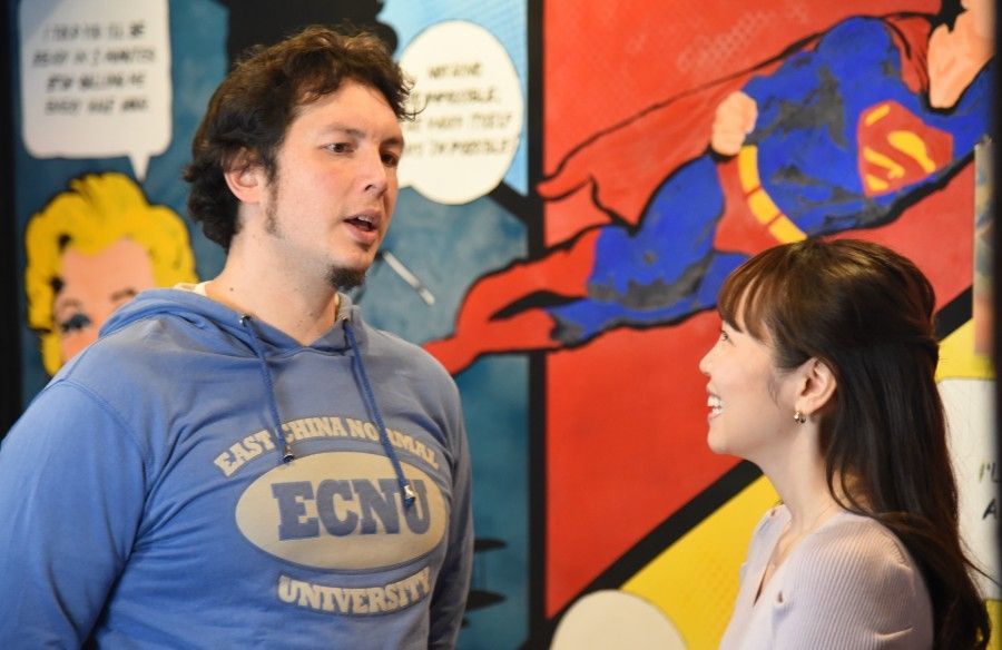 A man and a woman are standing in front of a painting of superman