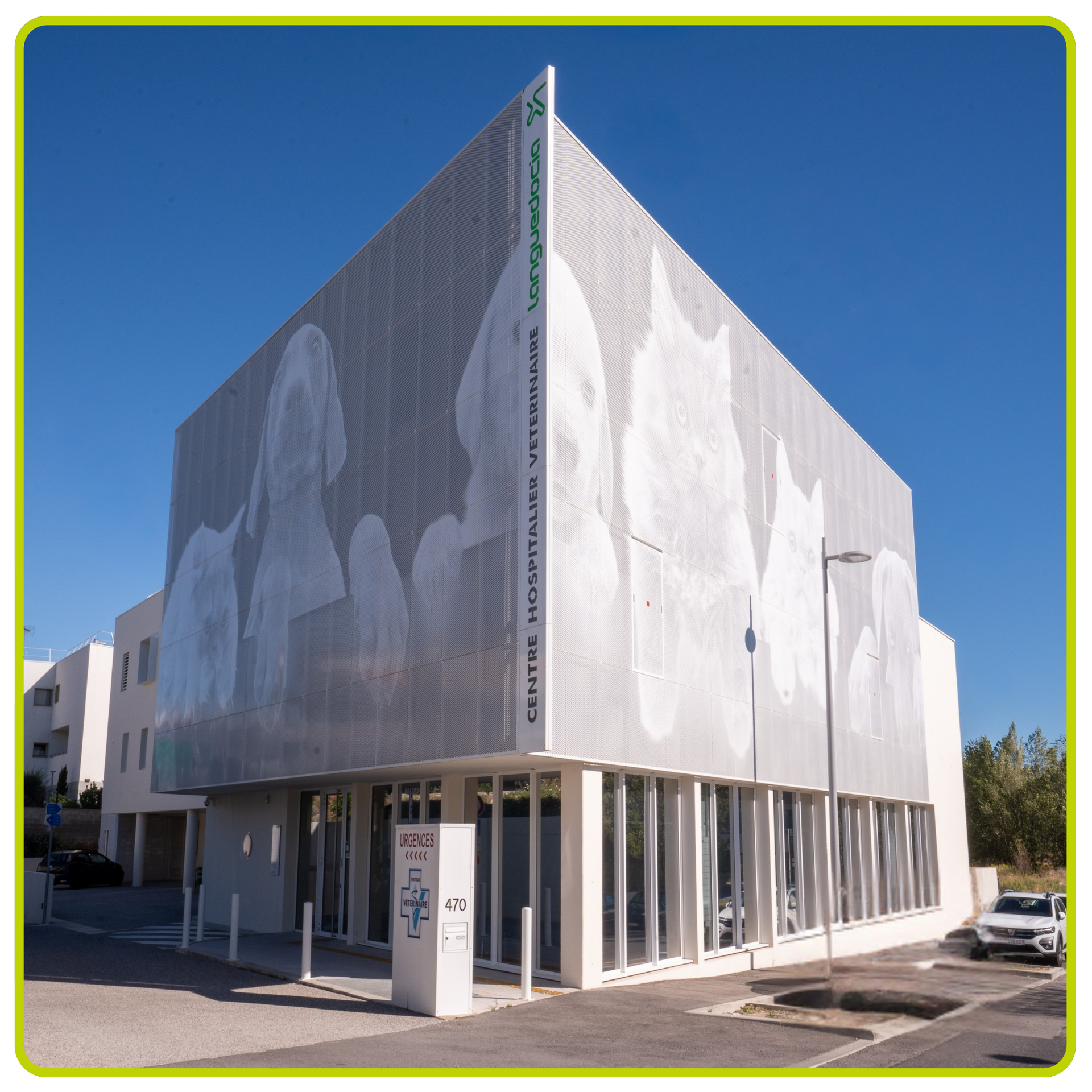 Bâtiment moderne orné d'une grande fresque en niveaux de gris sur sa façade, sous un ciel d'un bleu limpide.