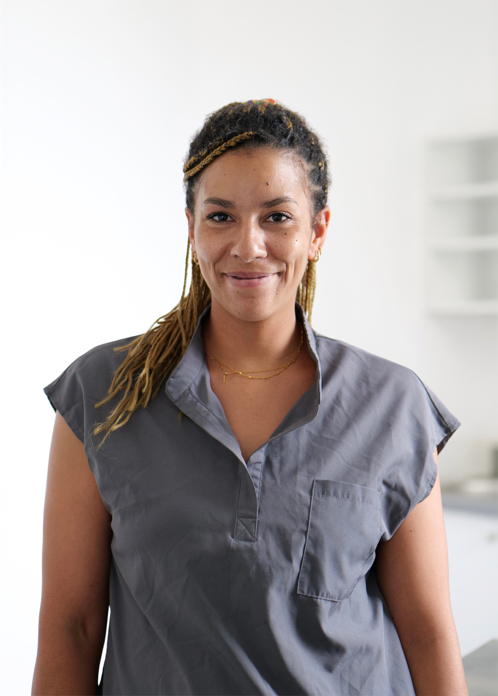 Femme en chemisier gris souriant dans un intérieur lumineux