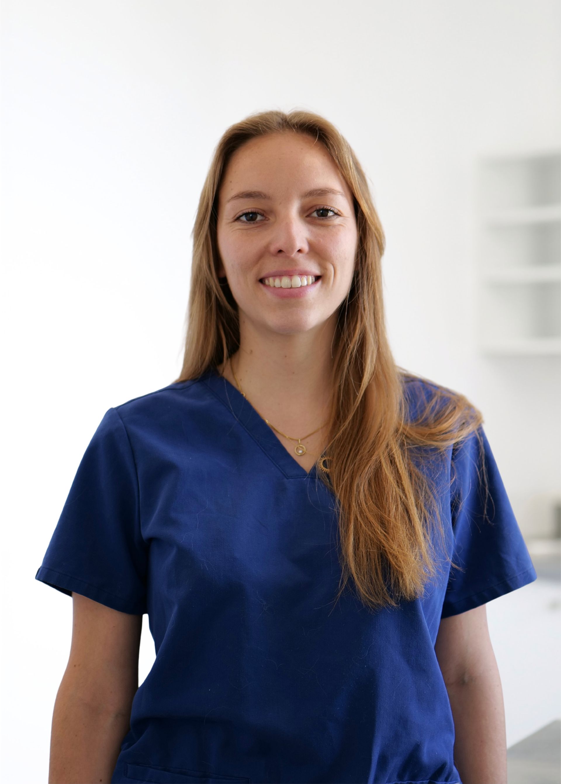 Femme en blouse bleue souriant dans une pièce d'un blanc éclatant