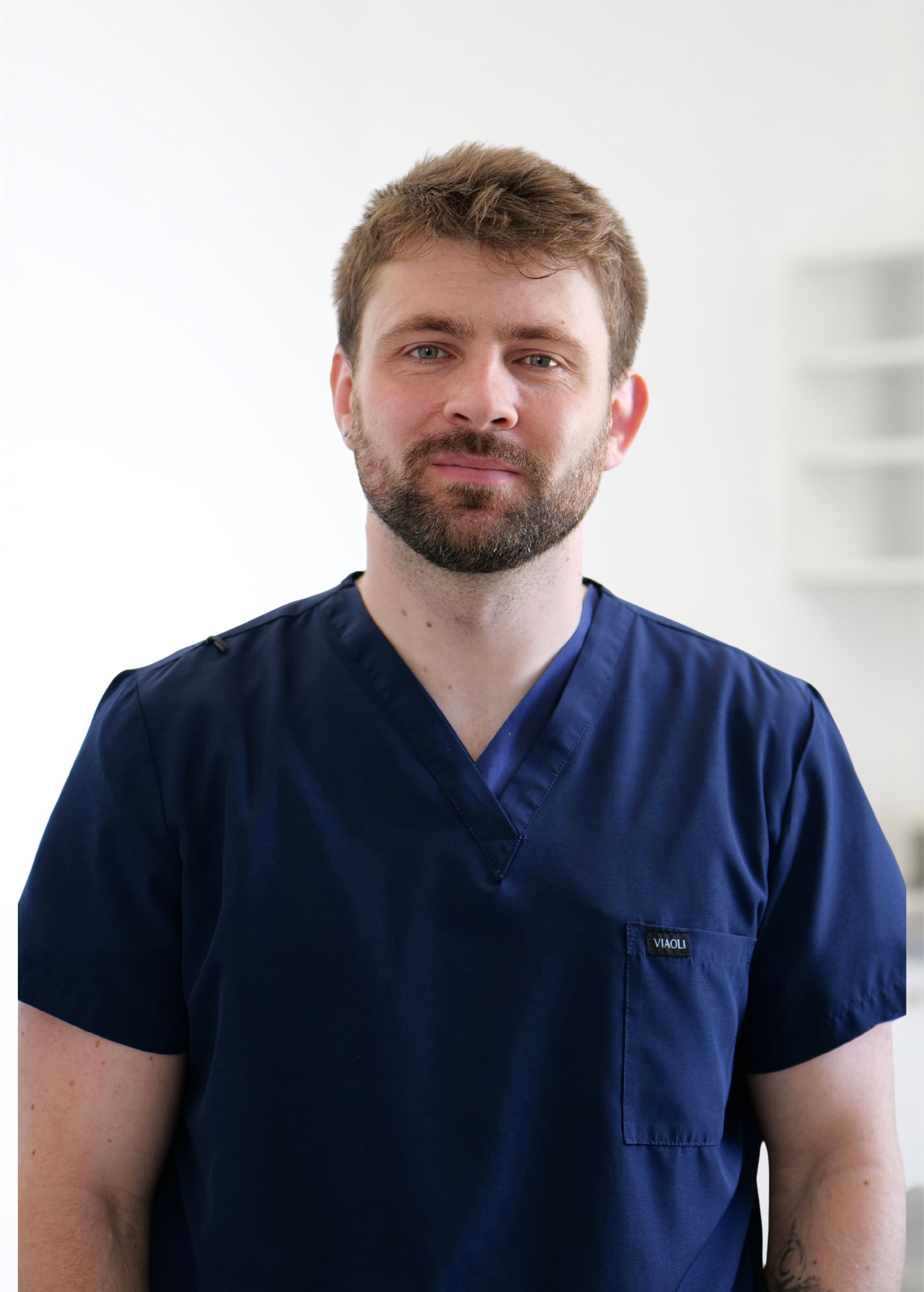 Personne en blouse médicale bleu marine, debout à l'intérieur sur fond blanc