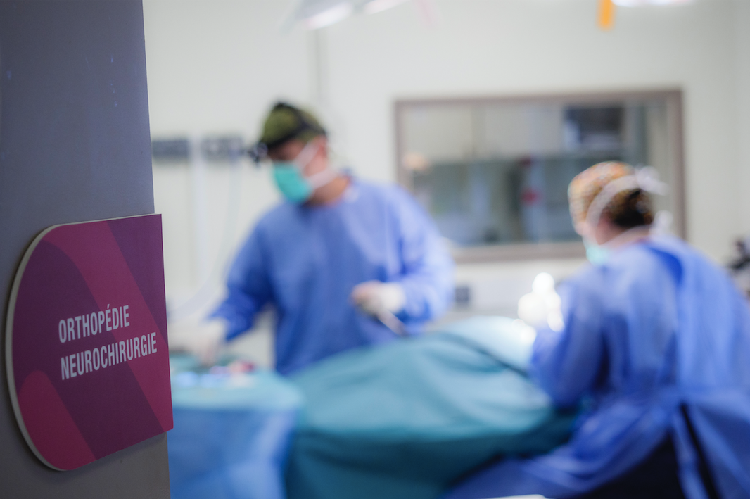 Salle d'opération avec du personnel médical masqué s'occupant d'un patient sur une table d'opération