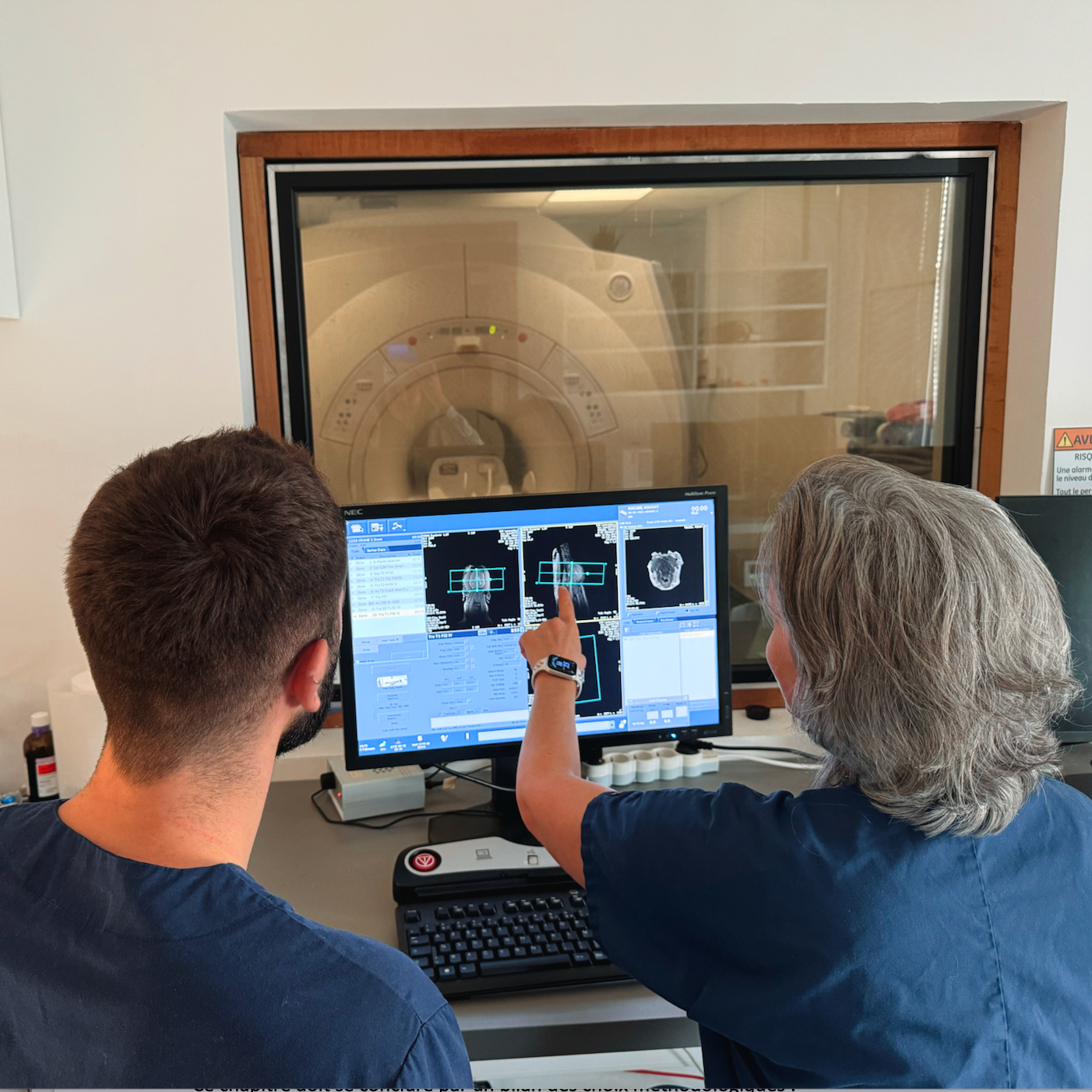 Deux personnes examinent des images de scanner cérébral sur un ordinateur dans une salle d'imagerie médicale
