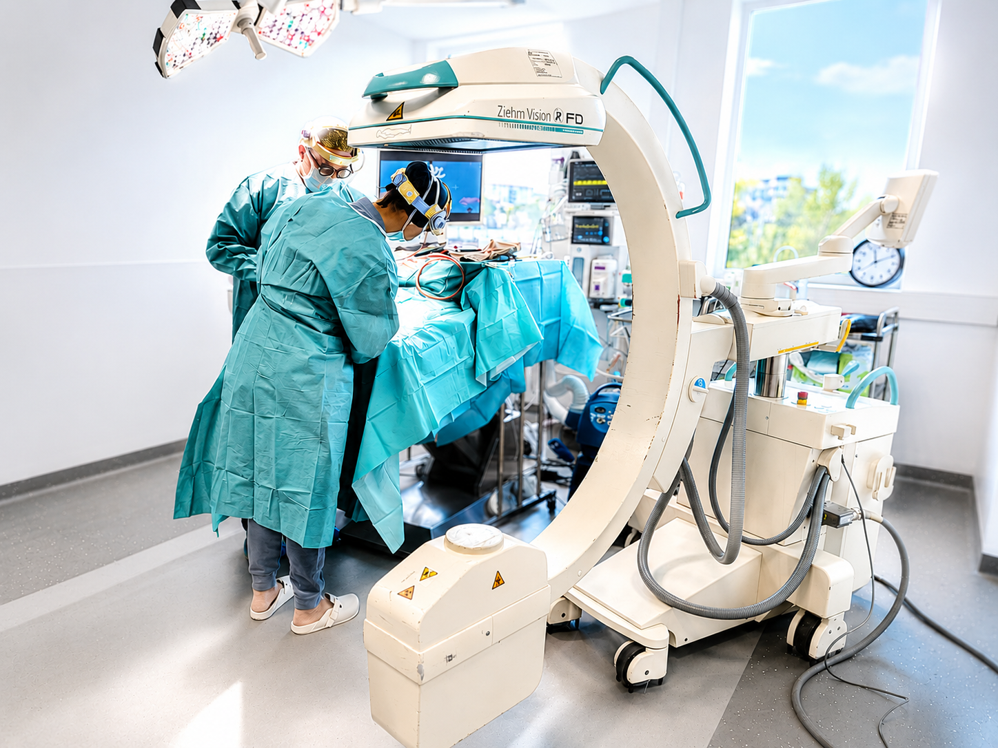 Une équipe médicale en blouses turquoise manipule un arceau chirurgical en C dans une salle d'opération