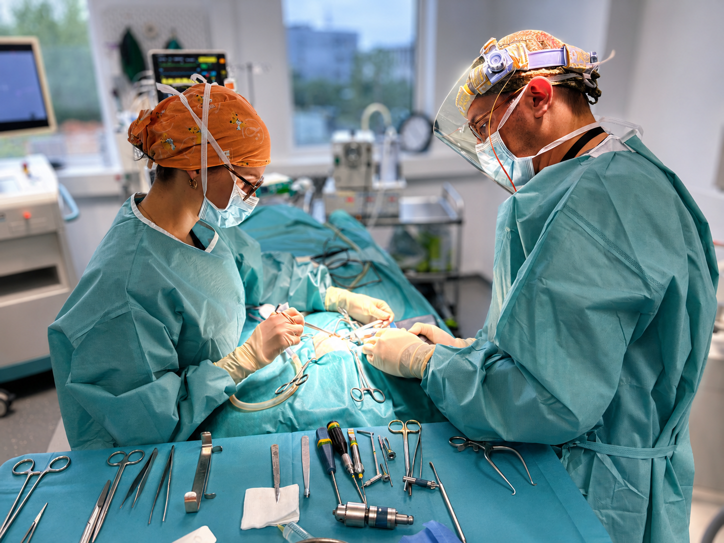 Deux chirurgiens en blouse turquoise opèrent dans une salle d'opération, entourés d'instruments chirurgicaux.