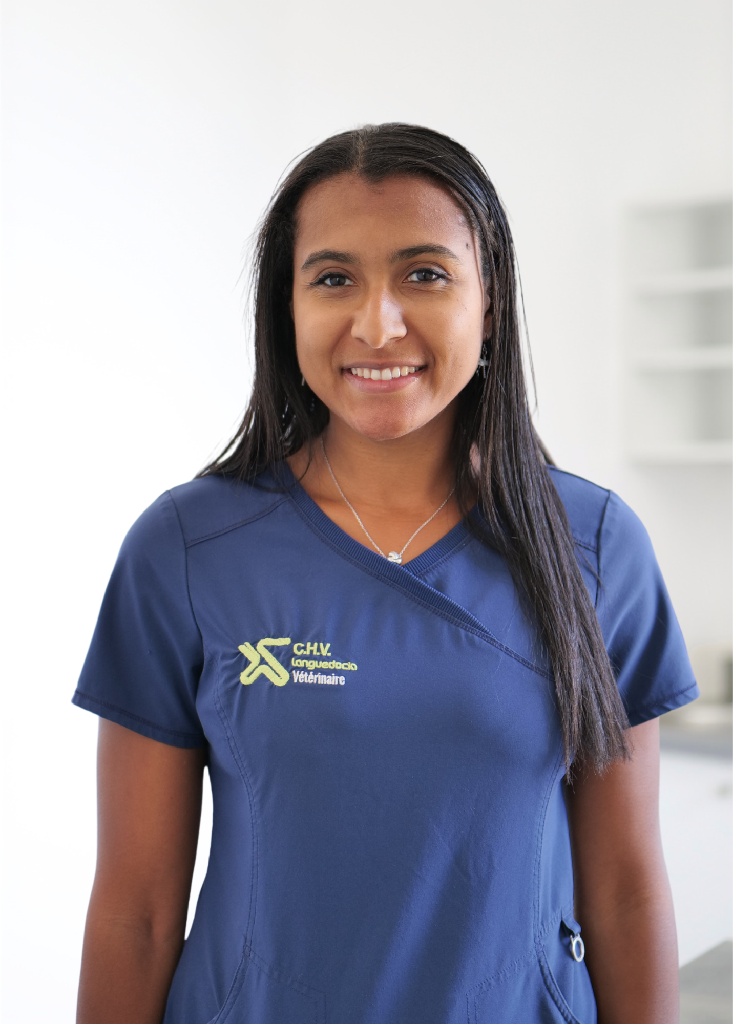 Personne souriante en blouse médicale bleu marine se détachant sur un fond blanc éclatant