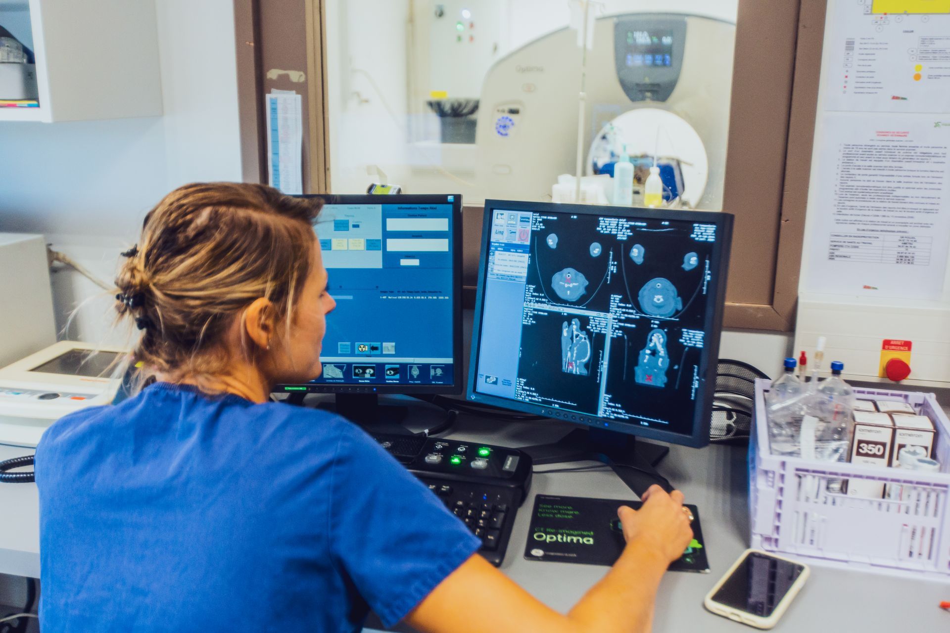 Personnel hospitalier à un poste de travail examinant des examens médicaux sur deux écrans.