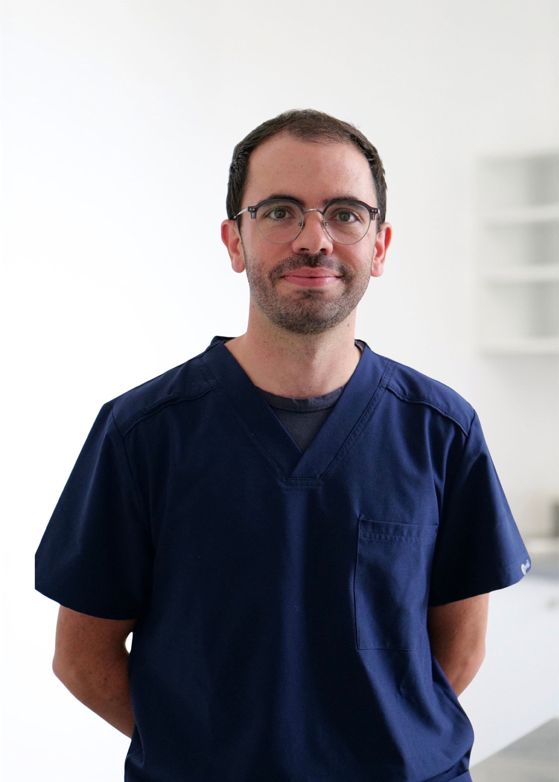 Personne en blouse médicale bleu marine se détachant sur un fond blanc éclatant.
