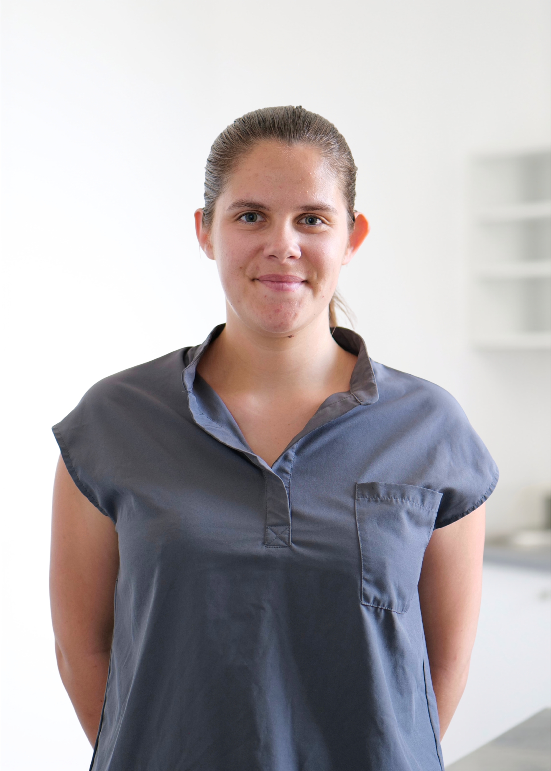 Personne debout à l'intérieur, sur fond clair, portant une chemise bleu foncé et arborant un léger sourire.