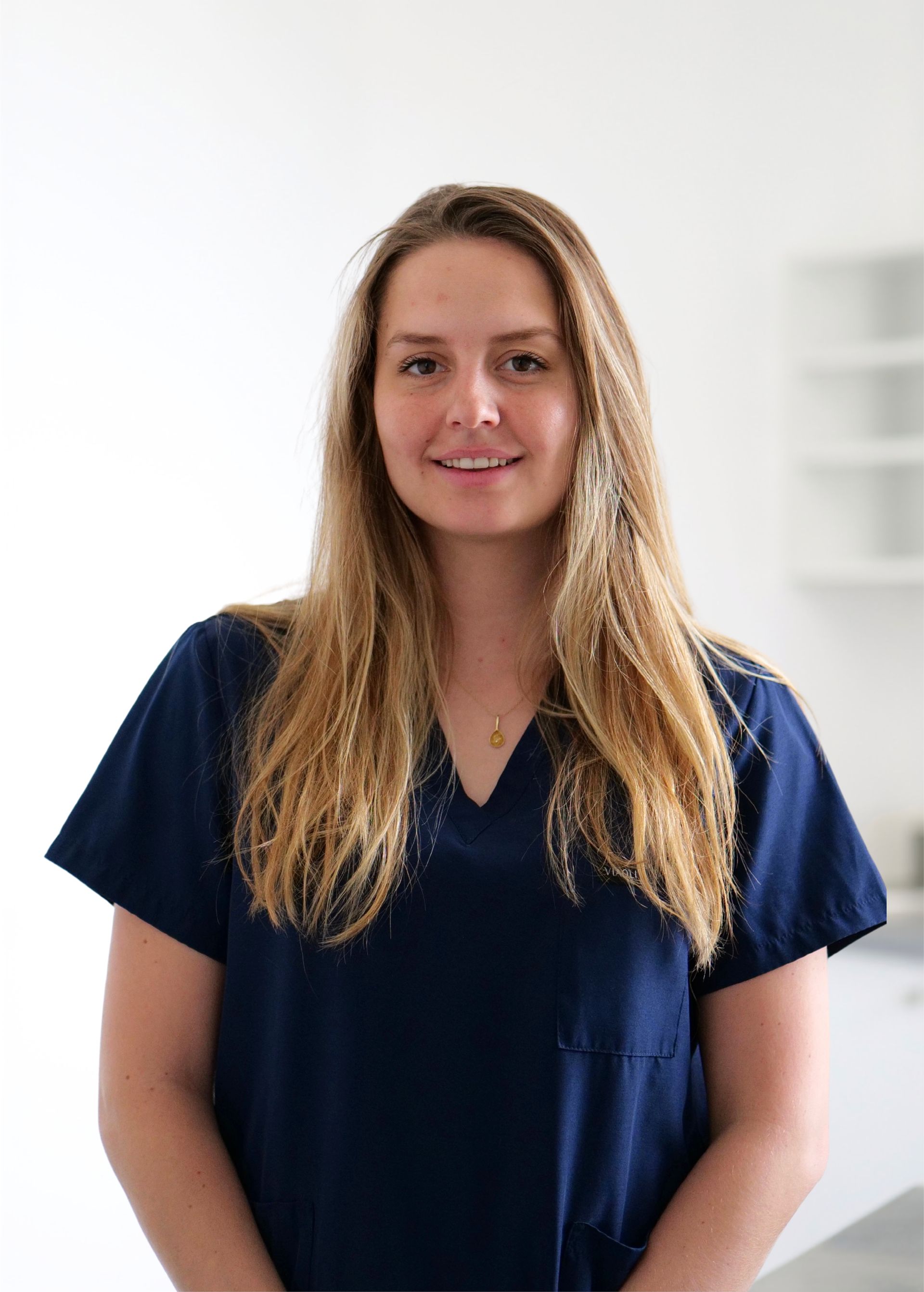 Personne souriante en blouse médicale bleu marine se détachant sur un fond blanc éclatant