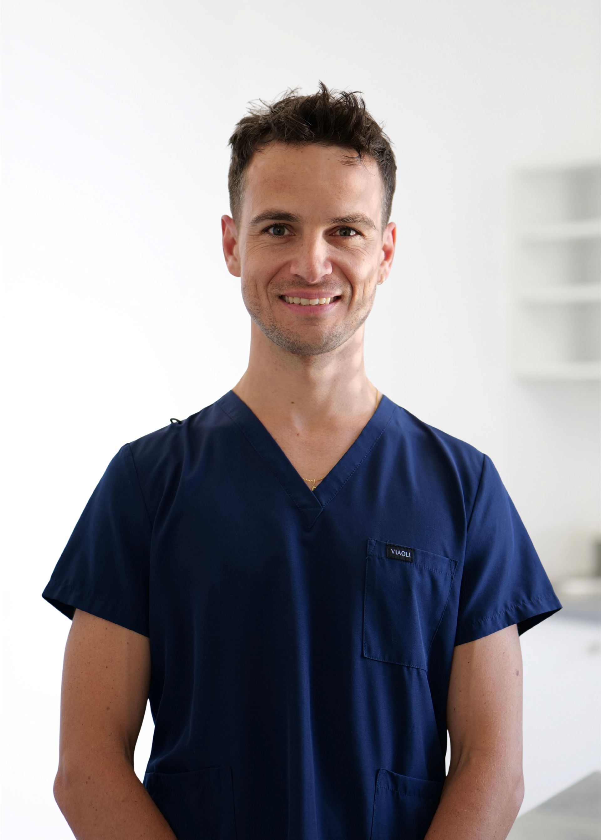 Personne en blouse médicale bleu marine souriant sur fond clair