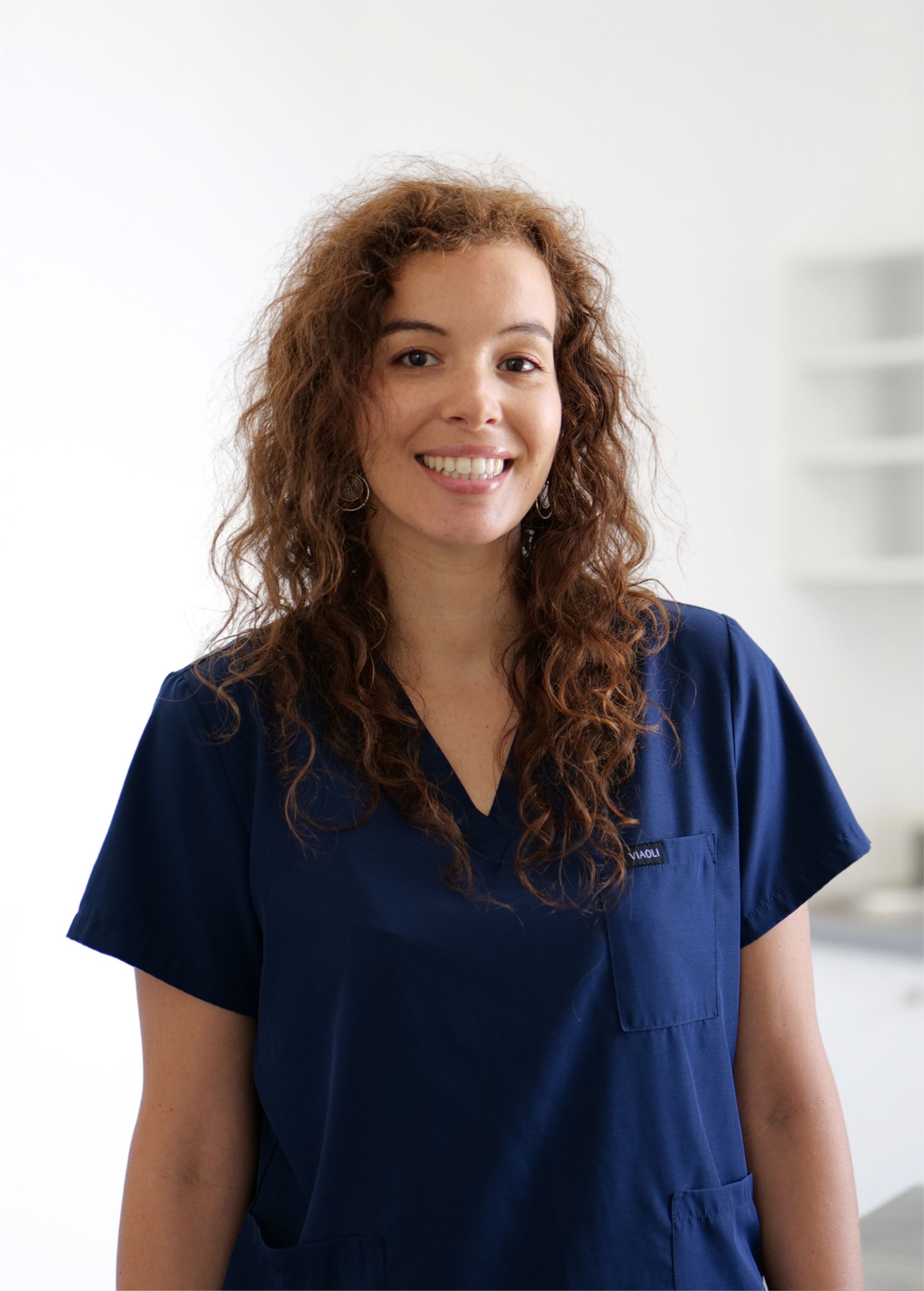 Personne souriante en blouse médicale bleu marine se détachant sur un fond clair