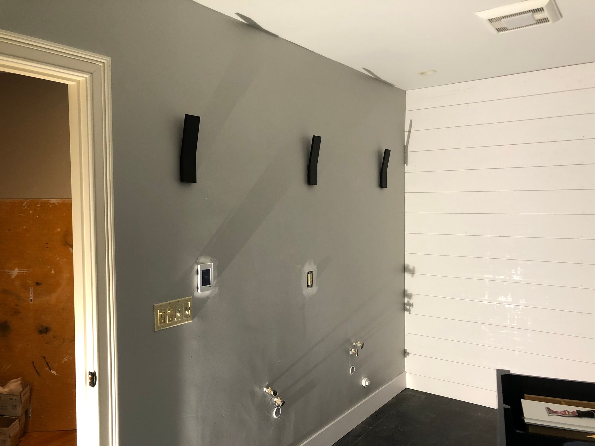 Empty bathroom with gray wall, white tile, and unfinished plumbing fixtures.