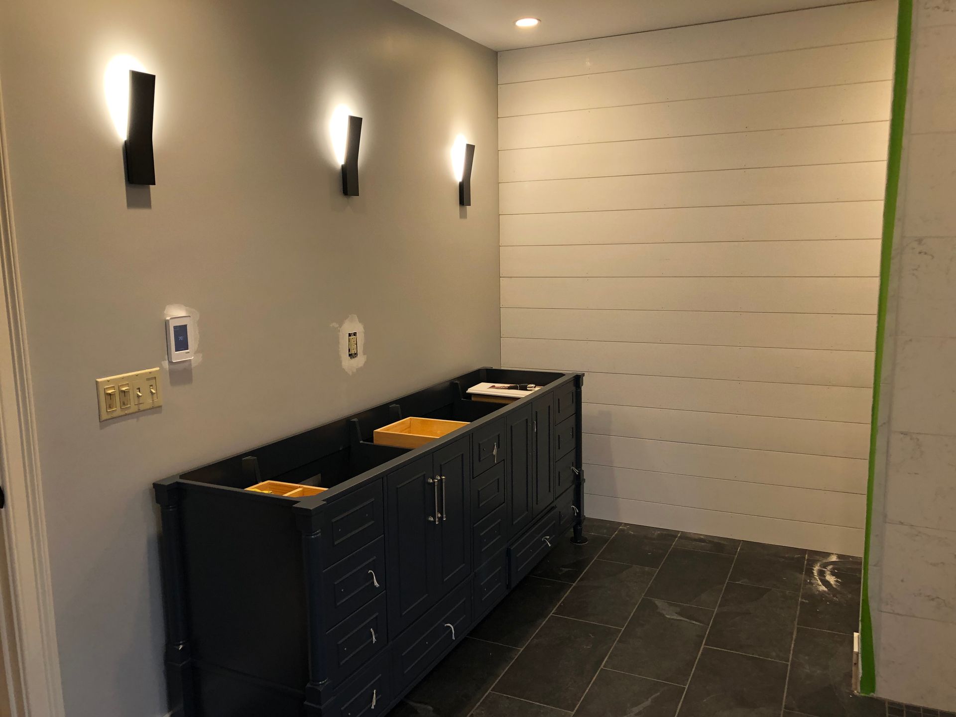 Renovated restroom with black stalls, wall sconces, and tiled floor