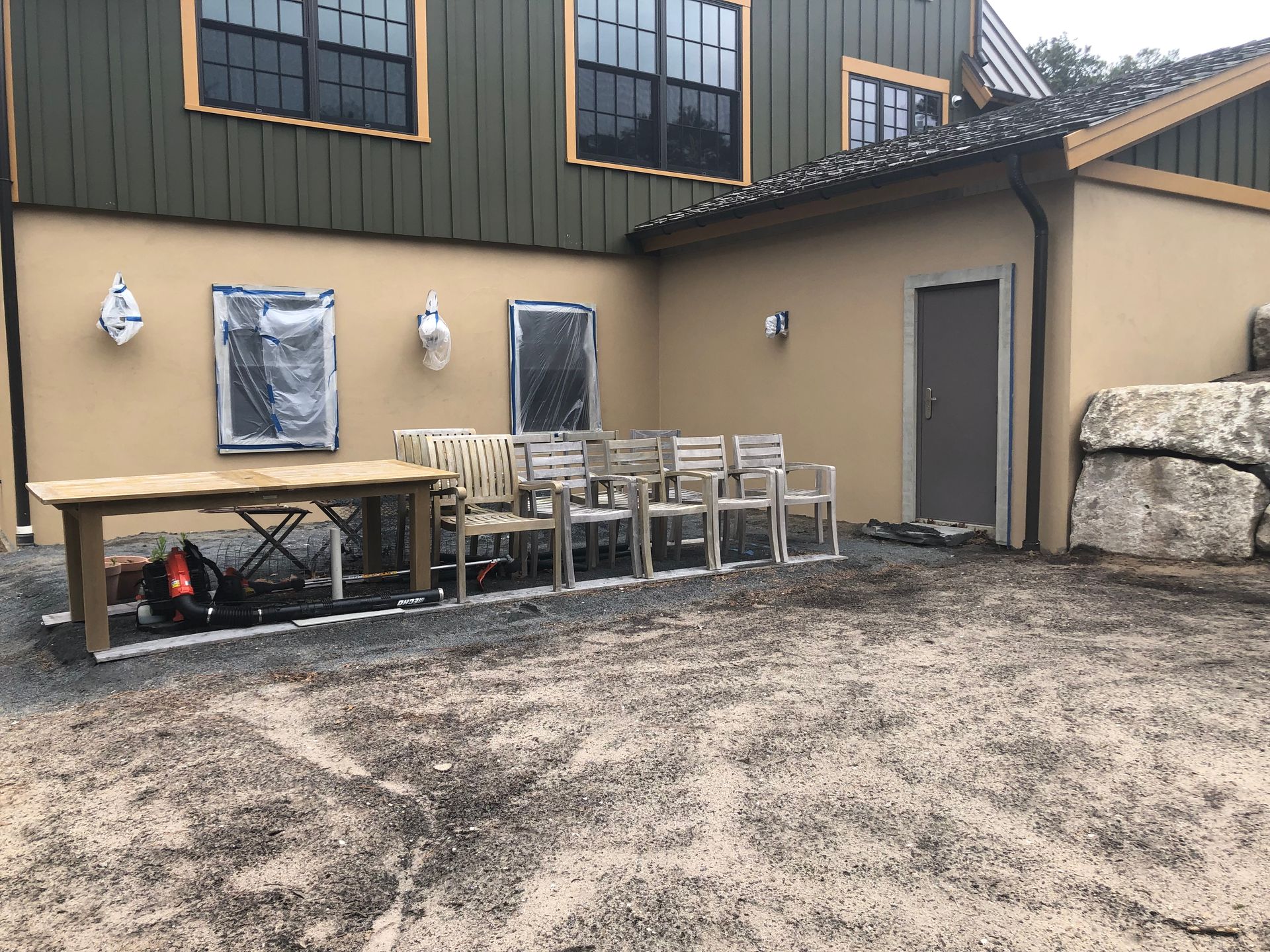 Outdoor patio with chairs, table, wall lights, and a side door beside a building.