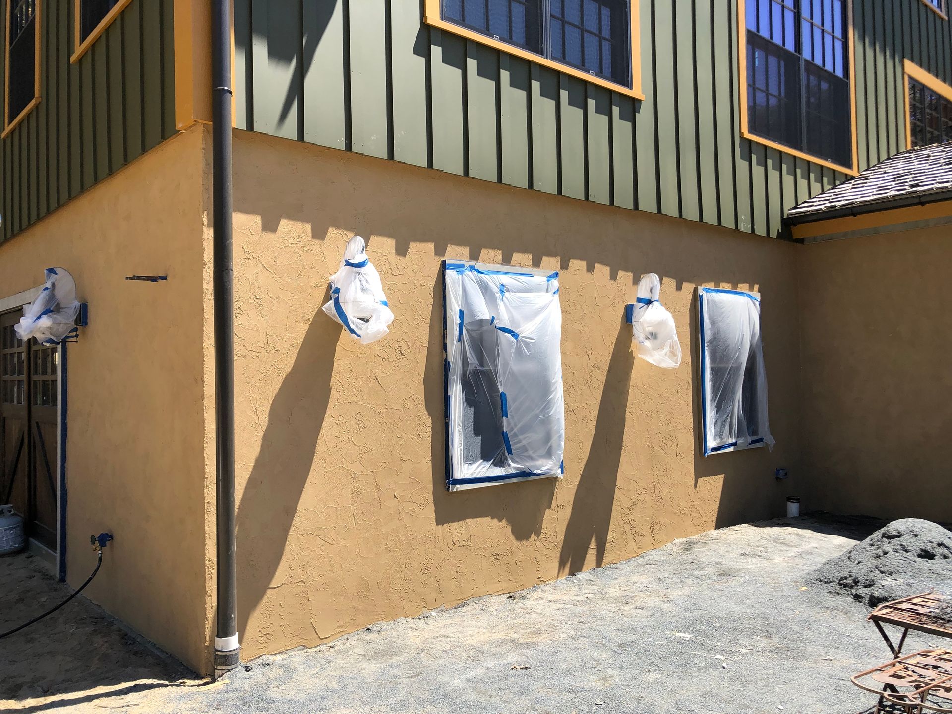 Hanging laundry on a tan stucco building wall with a green upper story and gravel ground