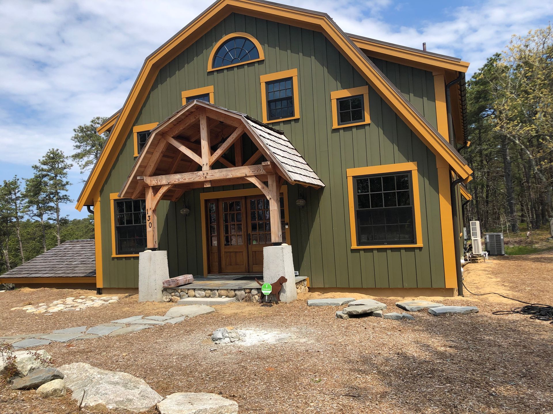 Green two-story house with wood trim and a covered front porch under construction.