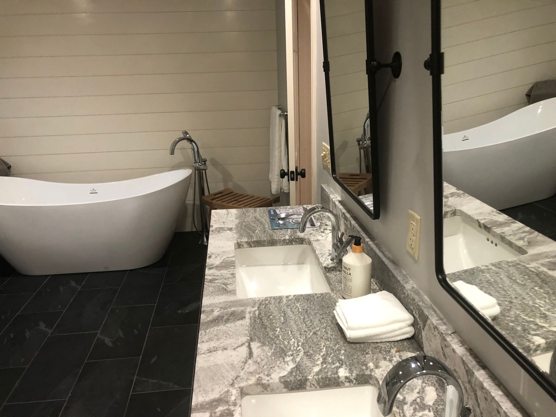 Modern bathroom with freestanding tubs, marble double vanity, and large wall mirror