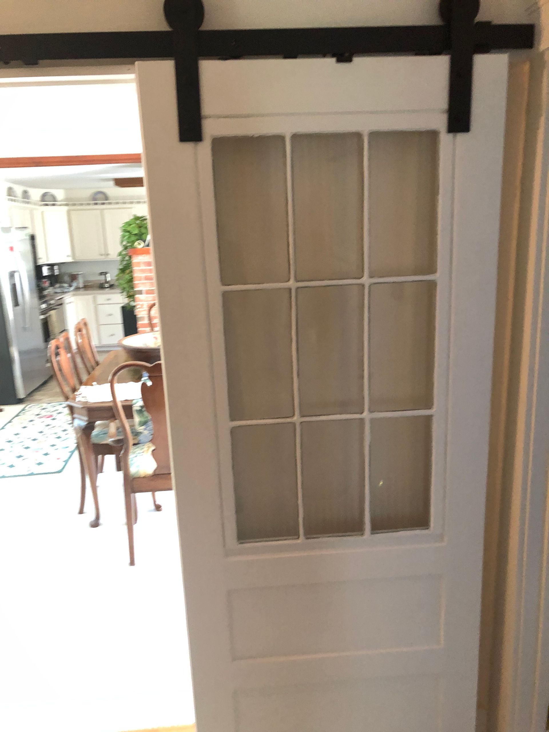 White paneled door with glass panes, opening into a bright kitchen and dining area