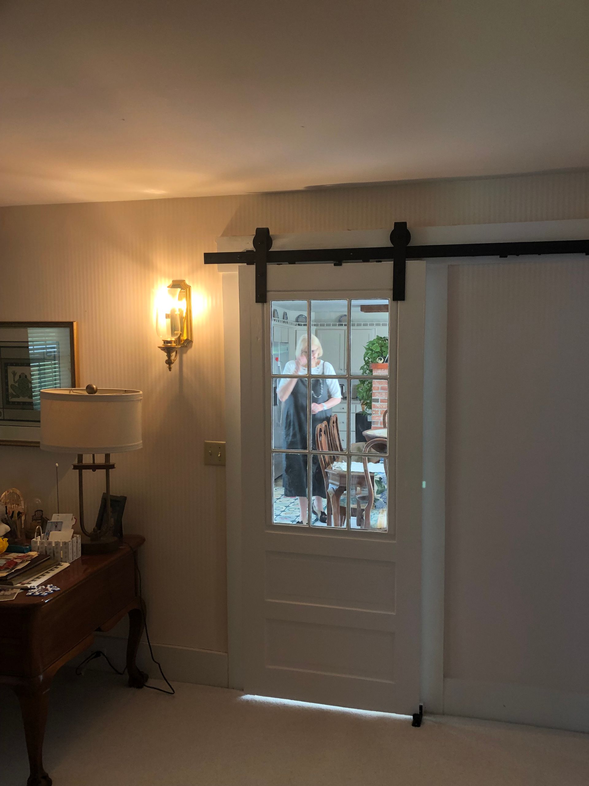 Interior room with white door and wall sconce, looking out to a patio through the glass panel.