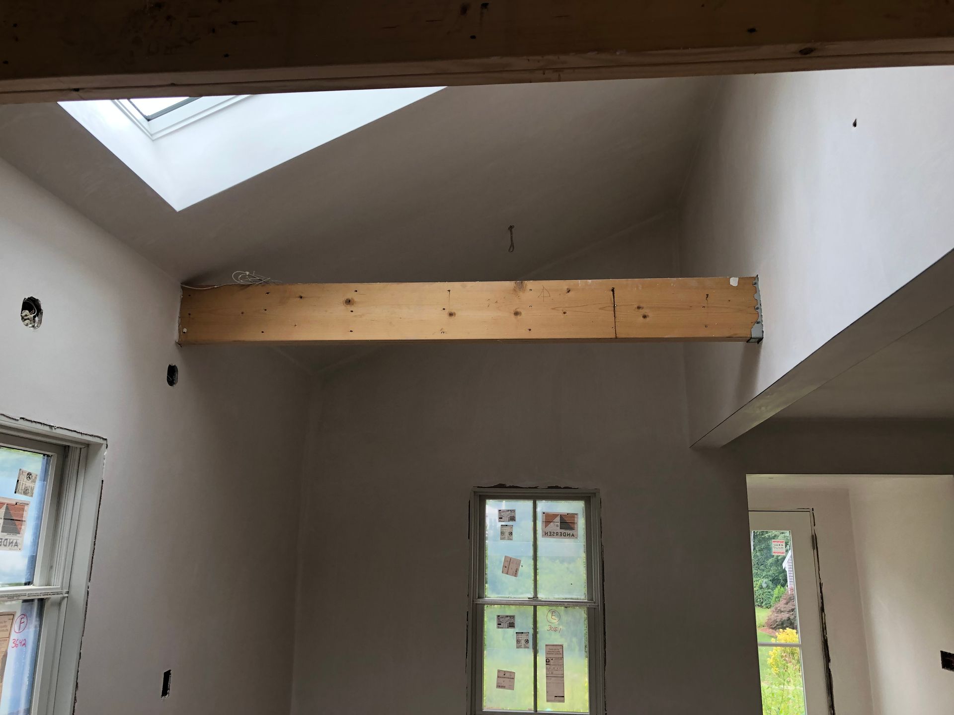 Interior room with skylight, exposed beam, and unfinished drywall walls