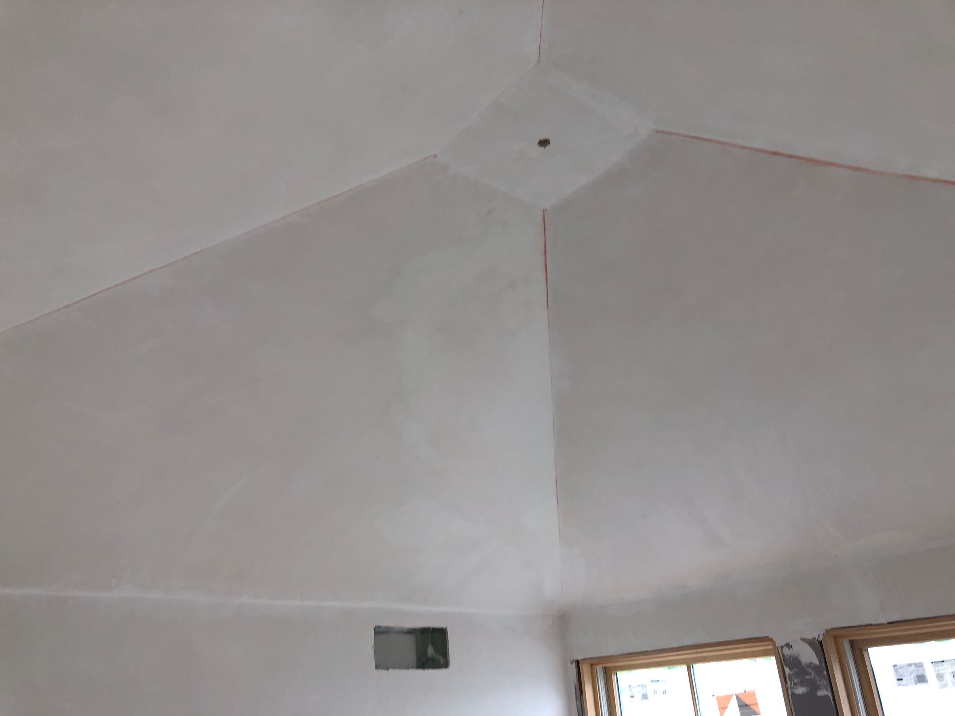 White vaulted ceiling with a small dark fixture and windows along the lower edge
