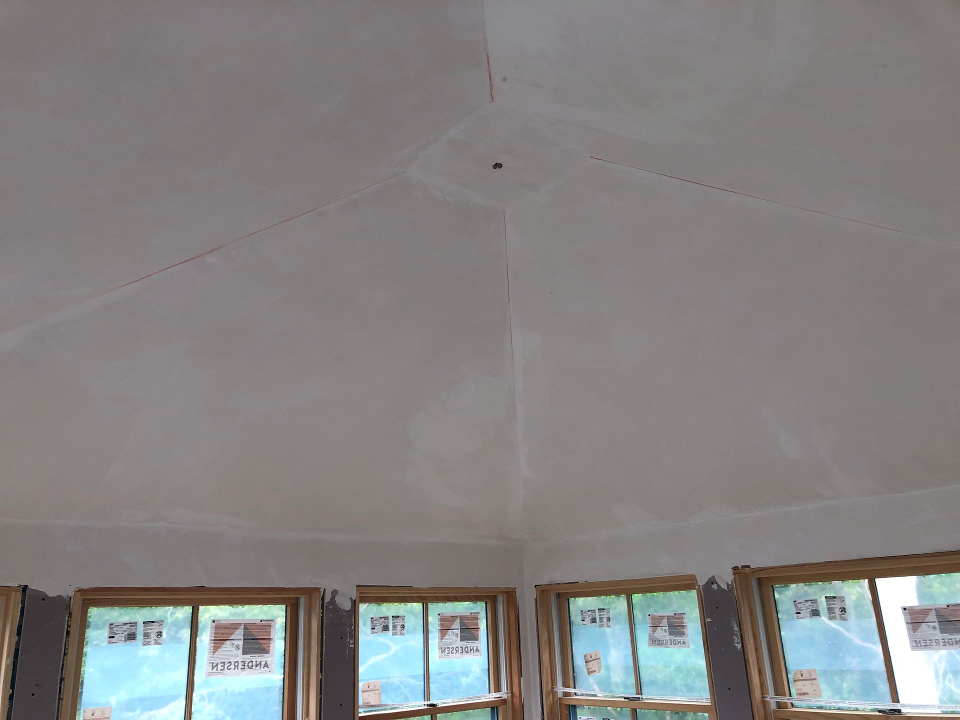 Interior ceiling with a central crack above a row of windows showing blue sky outside