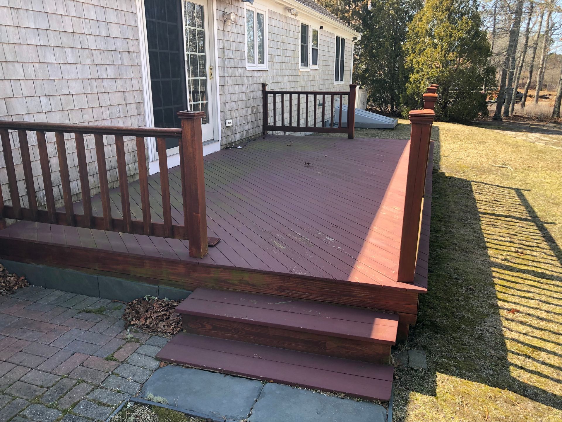 Wooden deck steps and railing beside a house in a sunny yard
