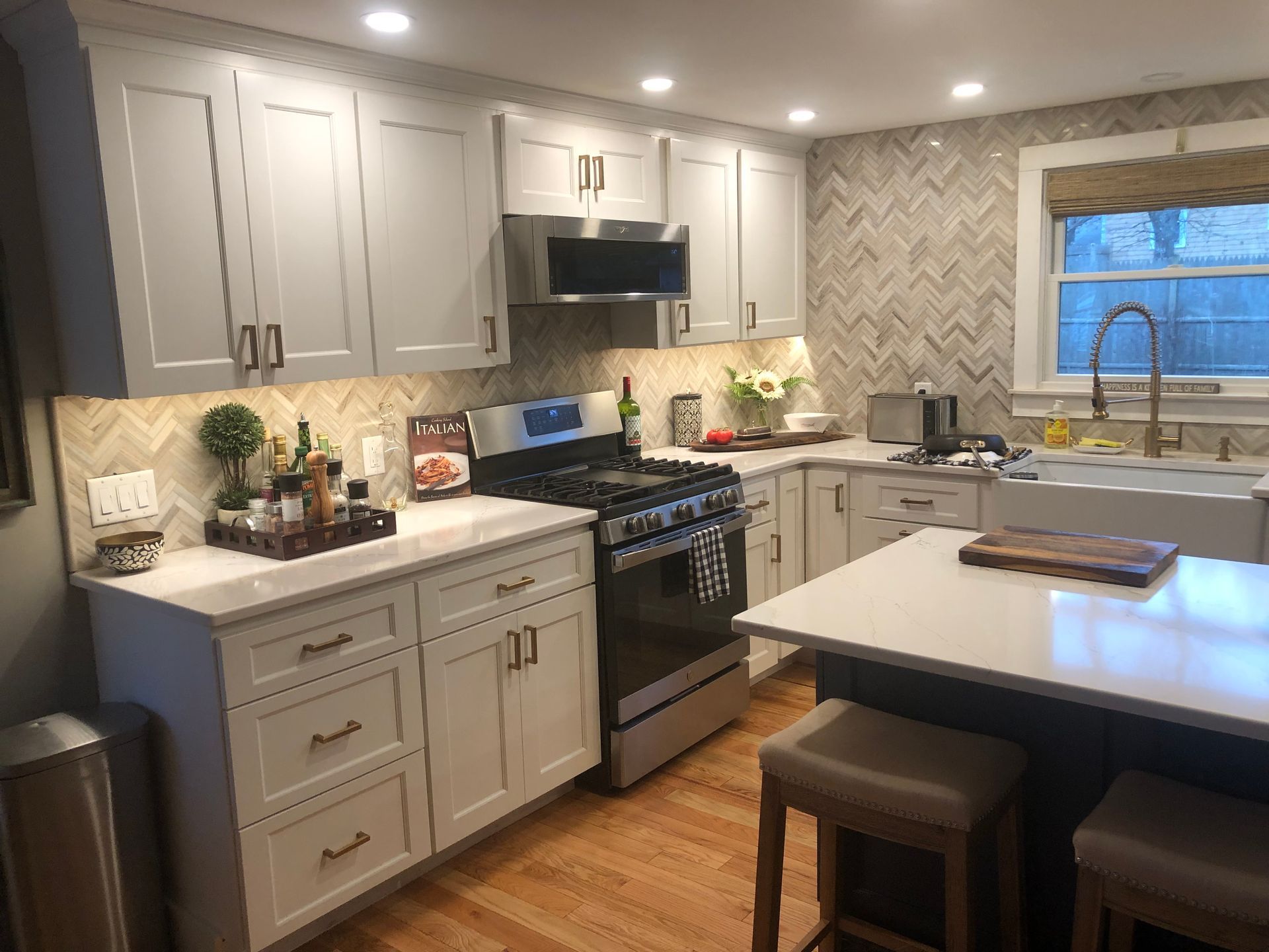 Modern kitchen with white cabinets, black stove, and a small island with stools.