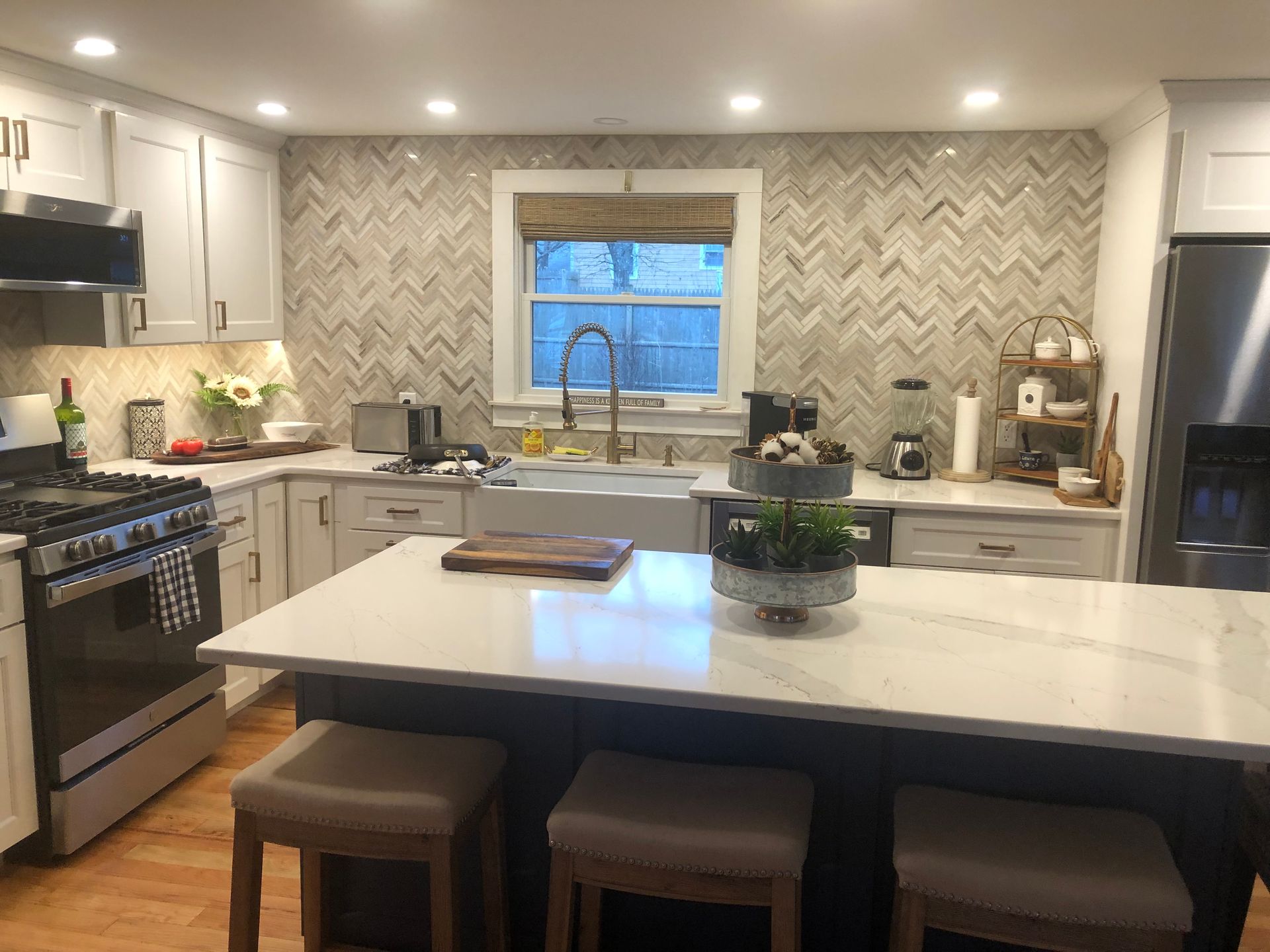 Modern kitchen with island, stainless steel appliances, patterned backsplash, and window over the sink