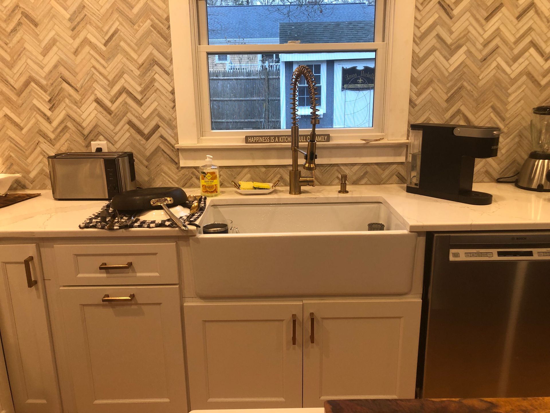 Kitchen with white farmhouse sink, patterned backsplash, gas stove, and dishwasher below the counter.