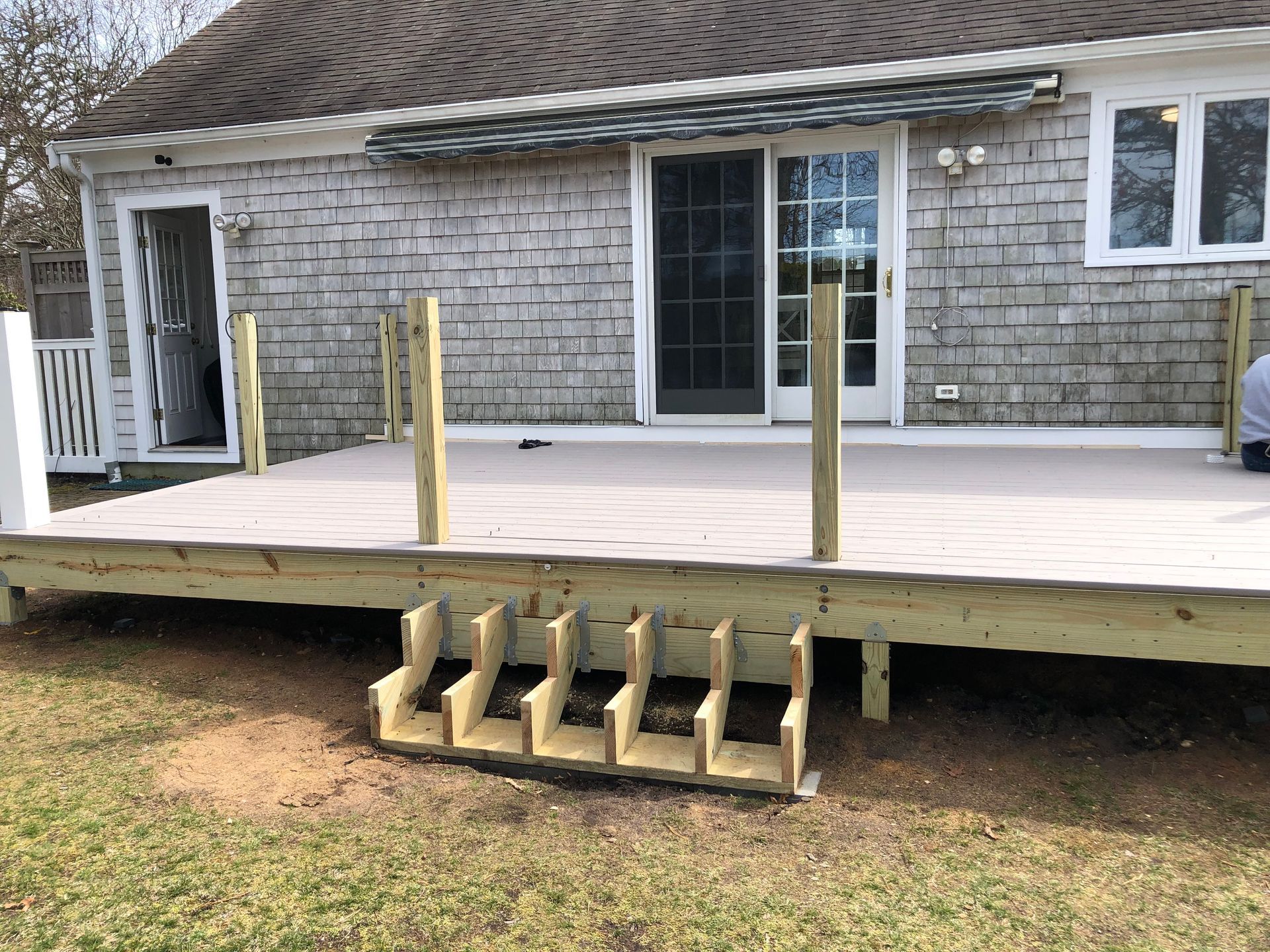 Back deck with temporary wooden ramp and posts in front of a house.
