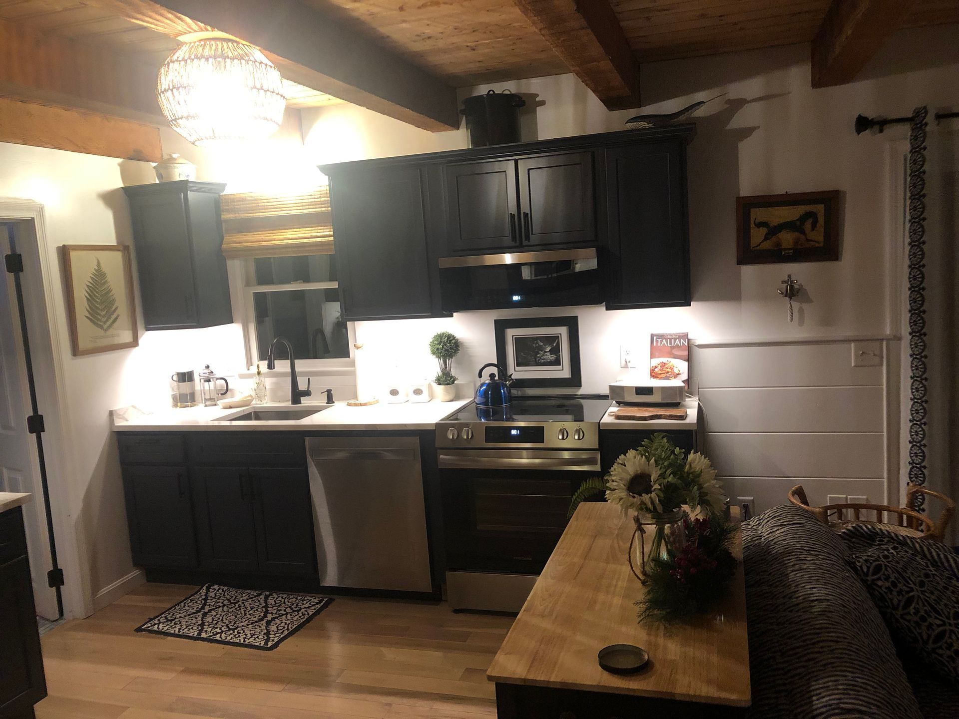 Cozy kitchen interior with dark cabinets, stainless stove, sink, and a wooden island with flowers