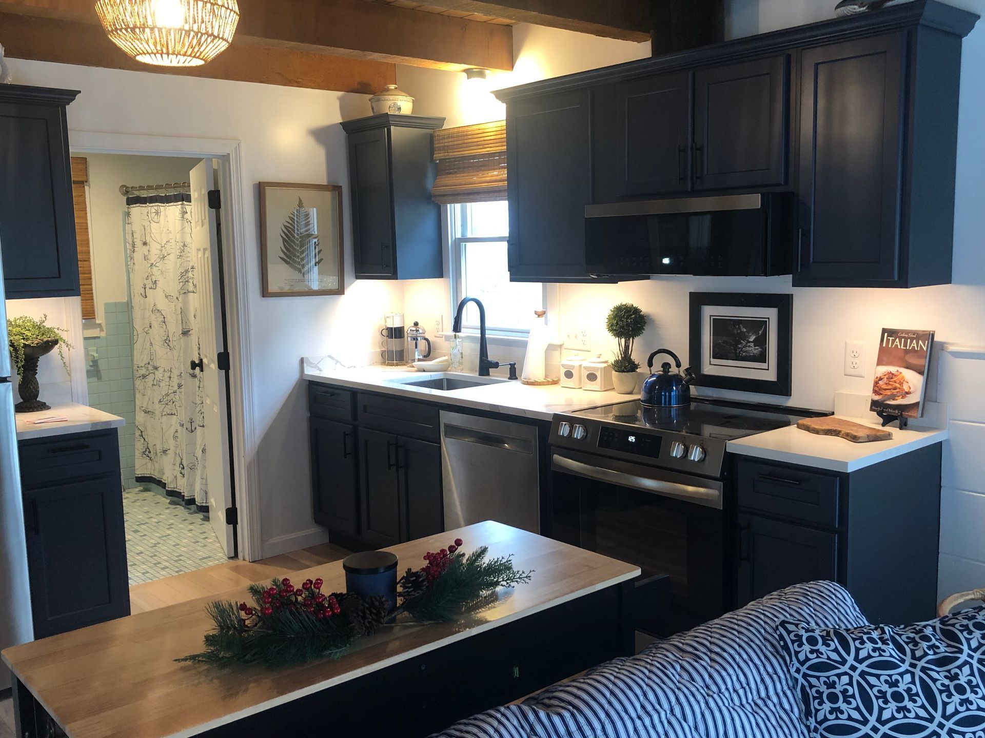 Cozy kitchen with dark cabinets, white countertops, island centerpiece, and adjacent living area.