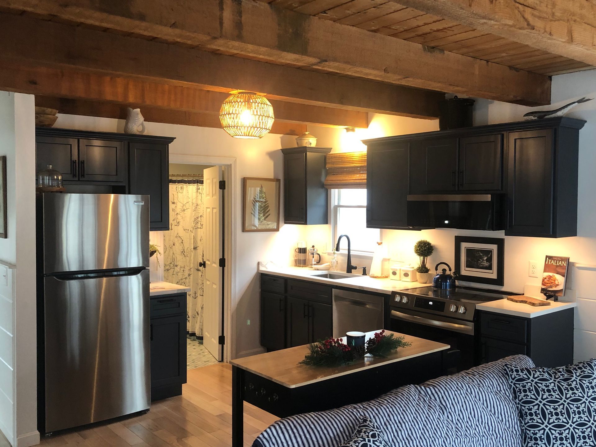 Cozy kitchen with stainless steel fridge, dark cabinets, island, and warm pendant lighting