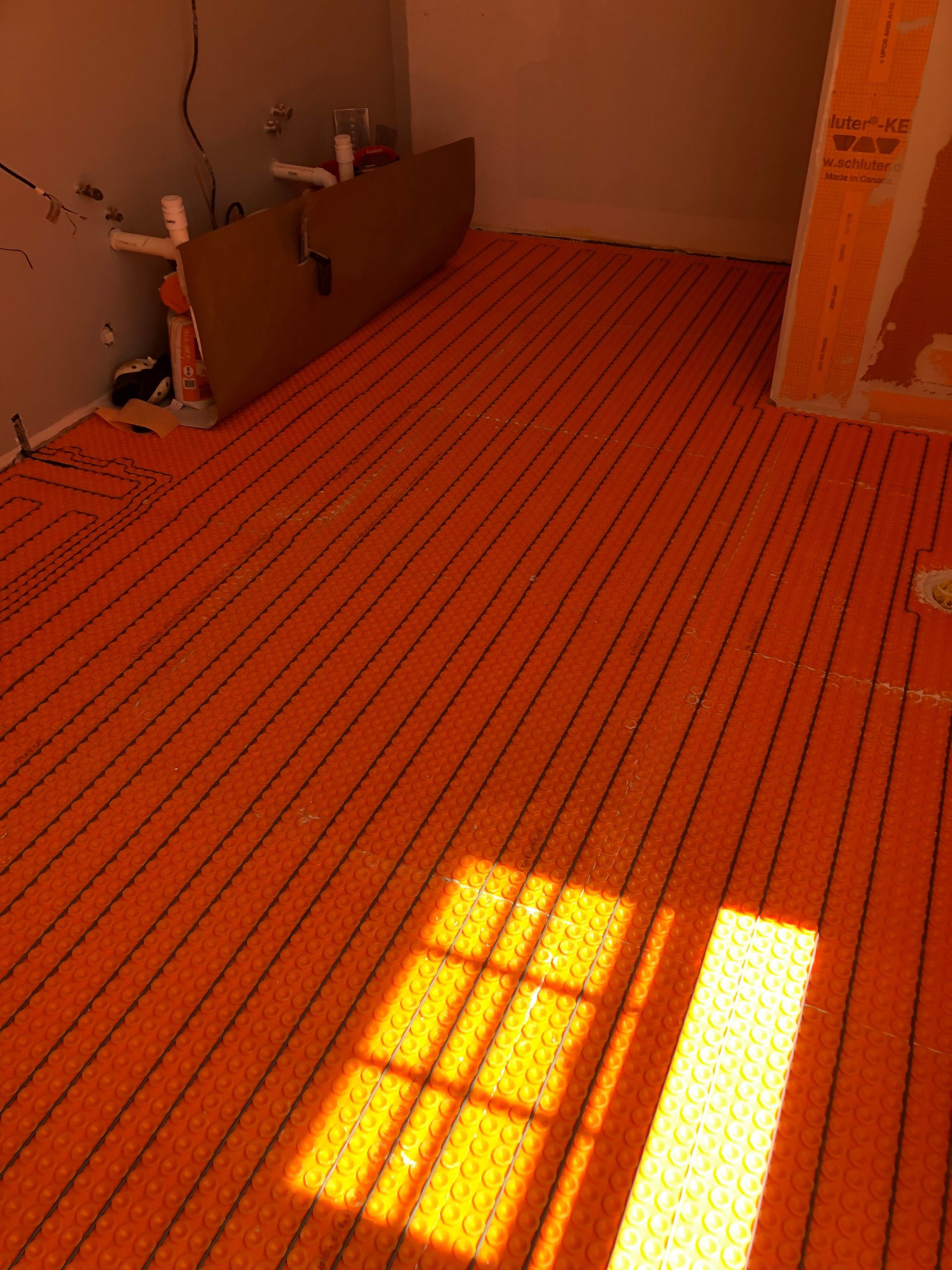 Sunlit empty room with orange striped carpet and a bright window shadow on the floor