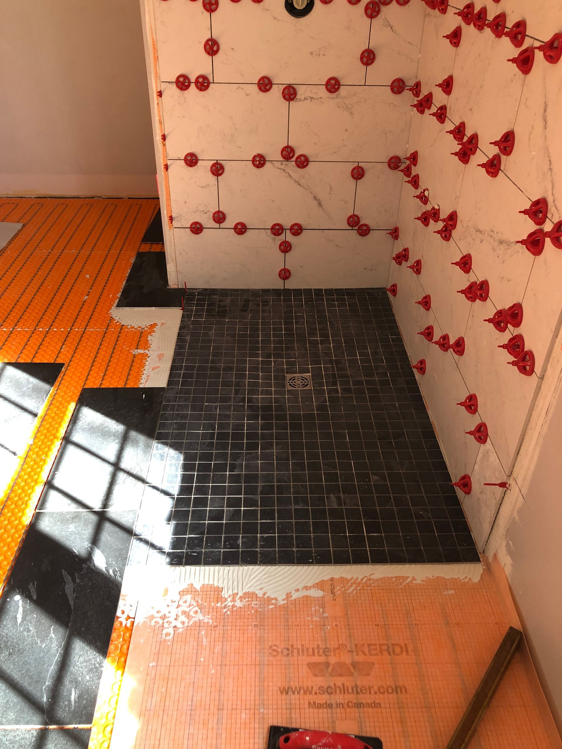 Bathroom floor with orange and black tile sections and red floral wall tiles