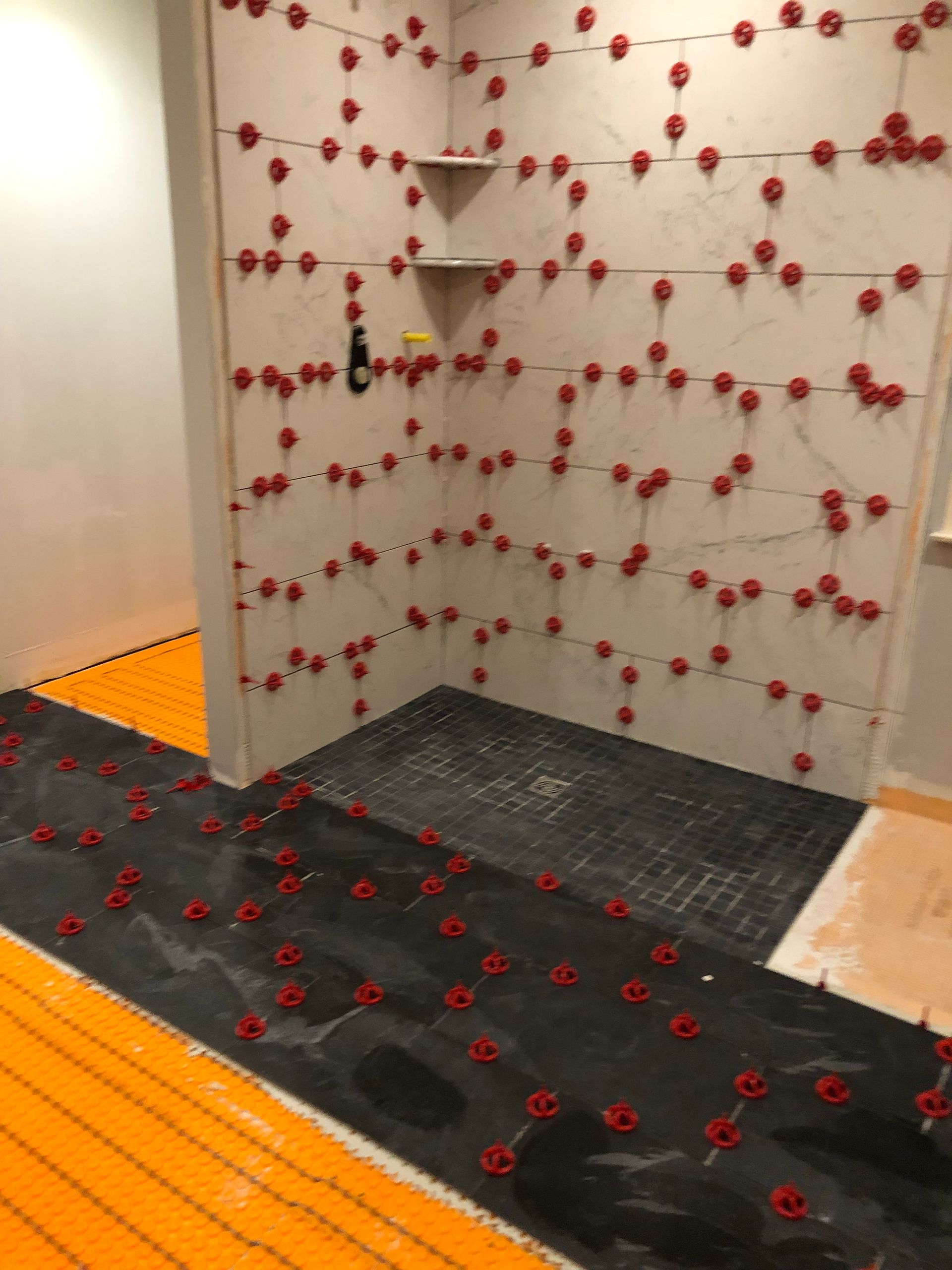 Indoor climbing wall with red holds and black-and-orange padded flooring.