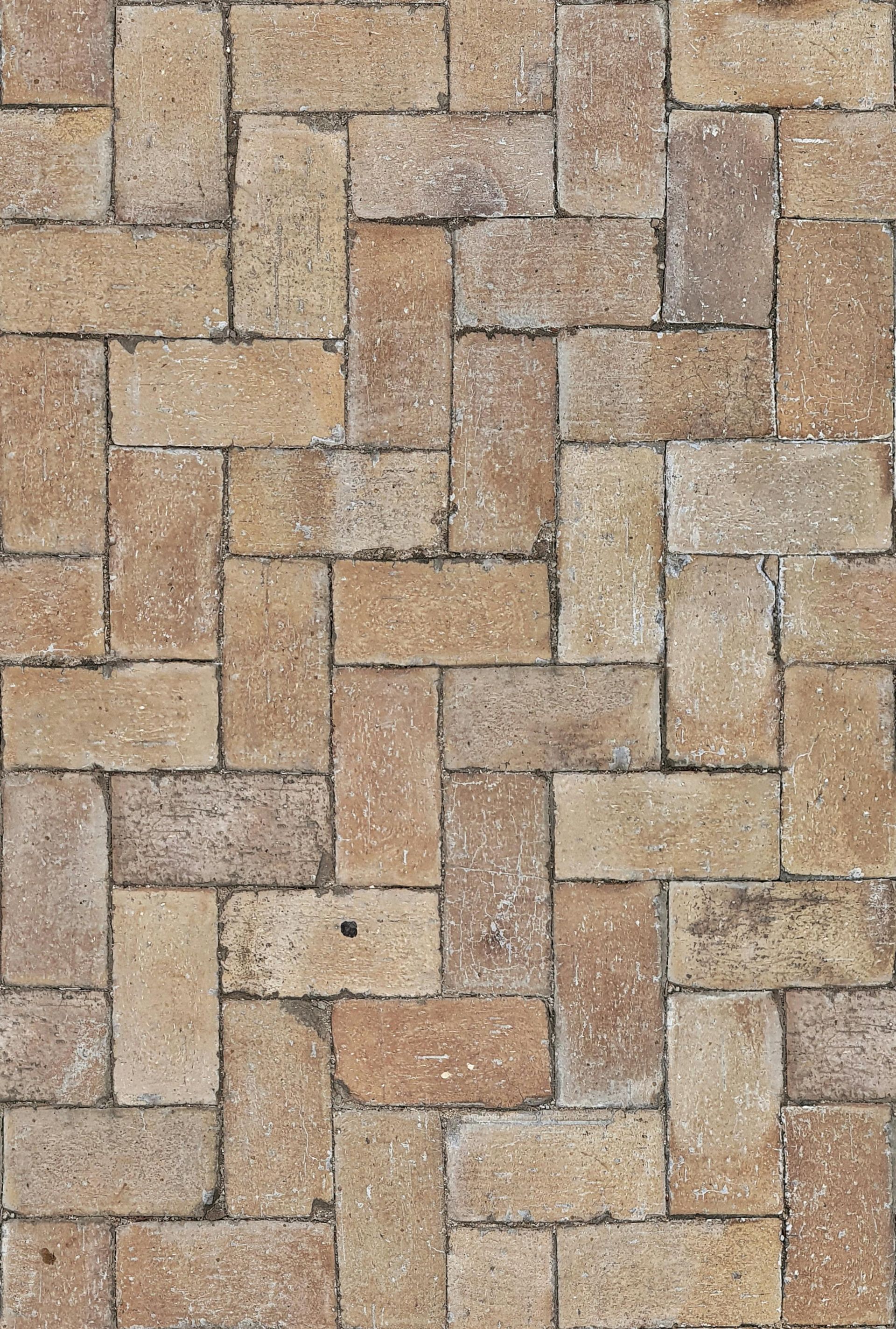 Tiled brick pathway with tan and brown bricks in a herringbone pattern.