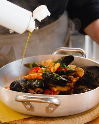 L'olio d'oliva viene versato in una padella con cozze e verdure.