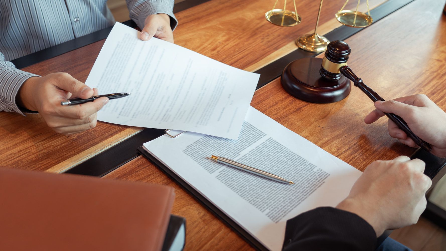 Two People Are Sitting at a Table With Papers and a Gavel — Hynes & McCormack In Murwillumbah, NSW