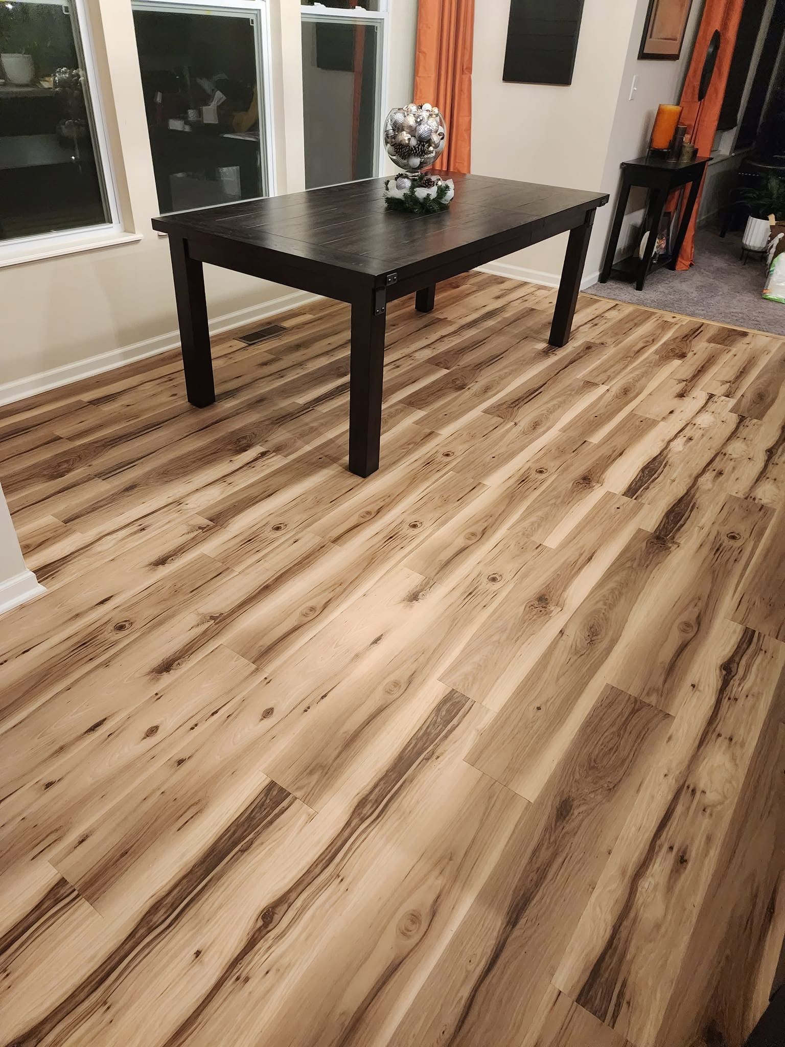 Modern room with light wood flooring, a black table, and a small centerpiece near sliding glass doors.