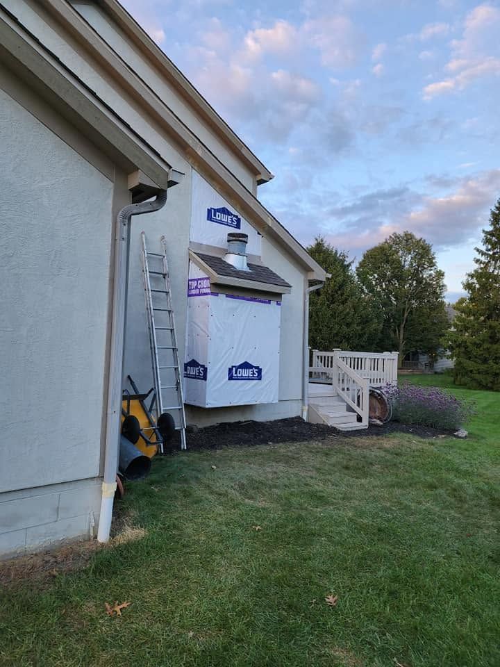 House exterior under construction with wrapped siding, ladder, and a small porch at dusk