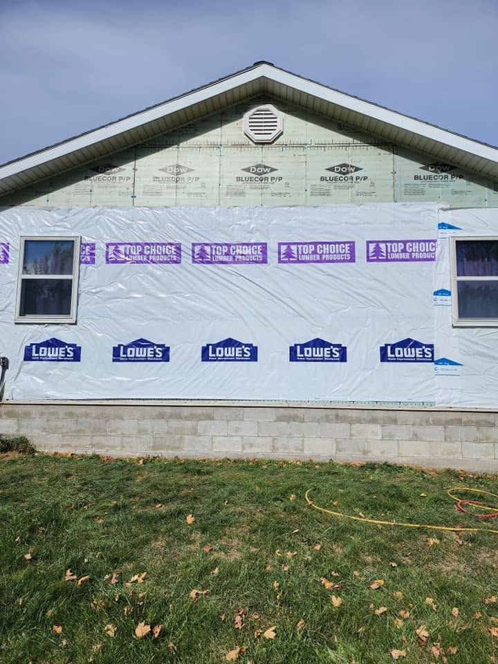 White house wall with purple flashing and blue Lobo house-wrap branding on a grassy yard